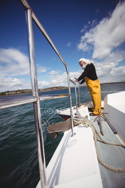 Seitenansicht des Fischers, der vom Fischerboot ins Meer blickt — Stockfoto