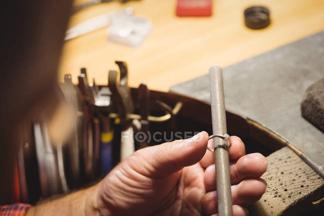 Primer plano de orfebre preparando anillo en taller - foto de stock