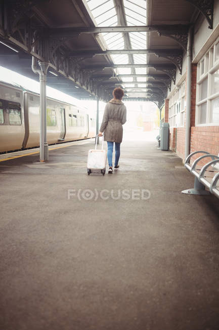 Full length of woman carrying luggage while walking at railroad station platform — Stock Photo