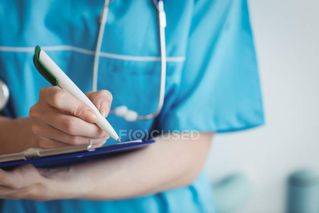 Nahaufnahme einer Krankenschwester beim Schreiben auf Klemmbrett im Krankenhaus — Stockfoto