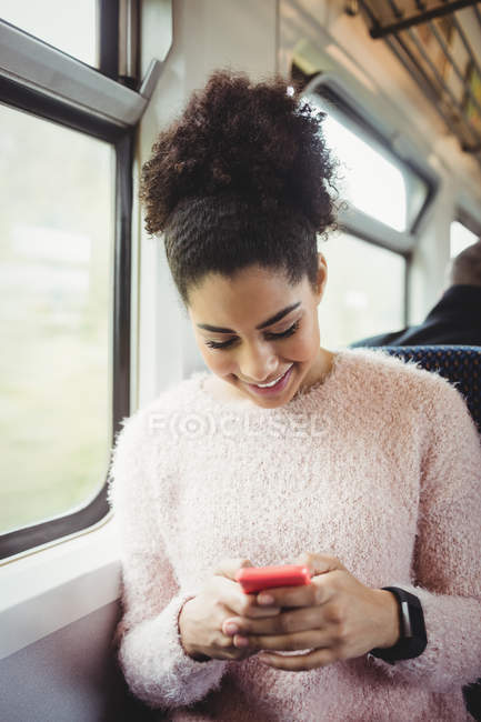 Усміхнена жінка використовує телефон, сидячи в поїзді — стокове фото