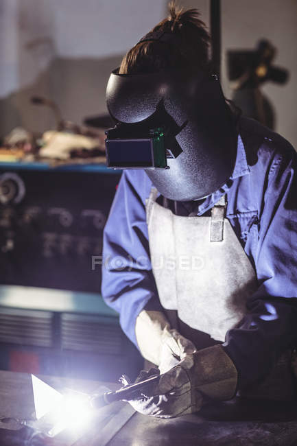 Female welder working on piece of metal in workshop — Stock Photo
