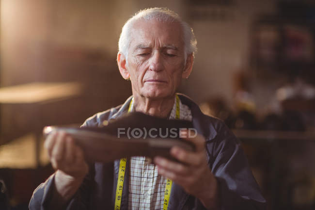 Shoemaker examining a shoe in workshop — Stock Photo
