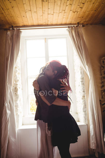 Romântico jovem casal abraçando contra a janela em casa — Fotografia de Stock