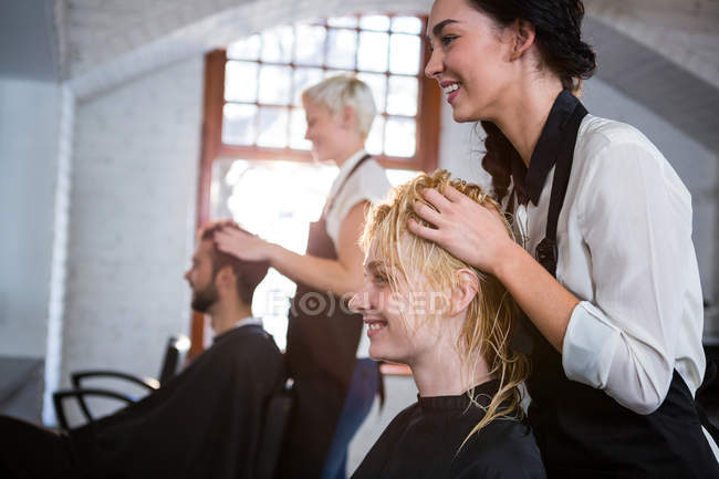 Усміхнене волосся стиліст масажує клієнтське волосся в салоні — стокове фото