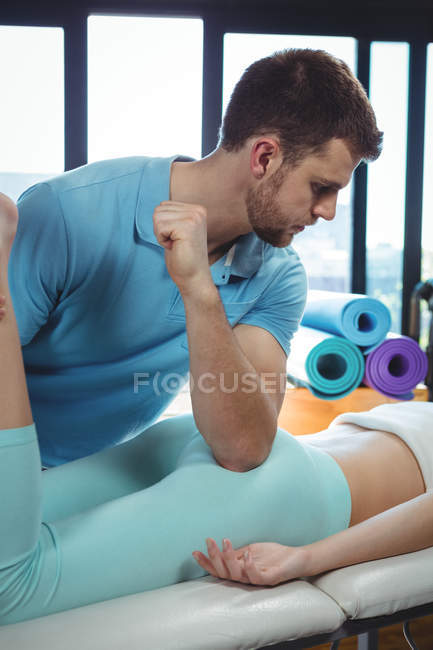 Male physiotherapist giving hip massage to female patient in clinic — Stock Photo