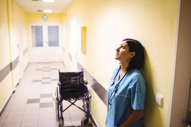 Enfermeira deprimida em pé no corredor hospitalar — Fotografia de Stock