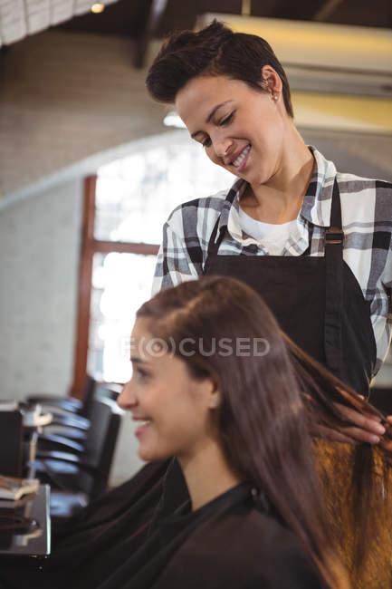 Peluquería sonriente trabajando en cliente en peluquería - foto de stock