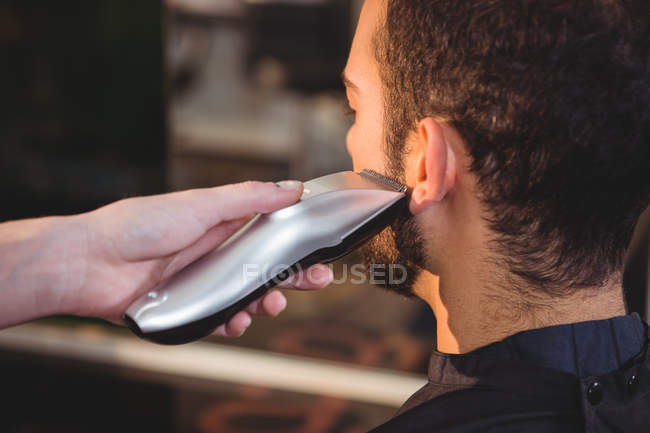 Recortado imagen de hombre consiguiendo su barba recortada en peluquería - foto de stock