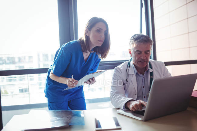 Doctor discussing with nurse over laptop at hospital — Stock Photo