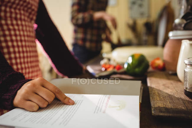 Frau liest zu Hause in der Küche ein Rezeptbuch — Stockfoto