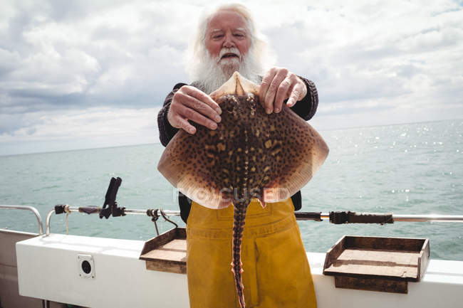Portrait of fisherman showing ray fish on boat — Stock Photo