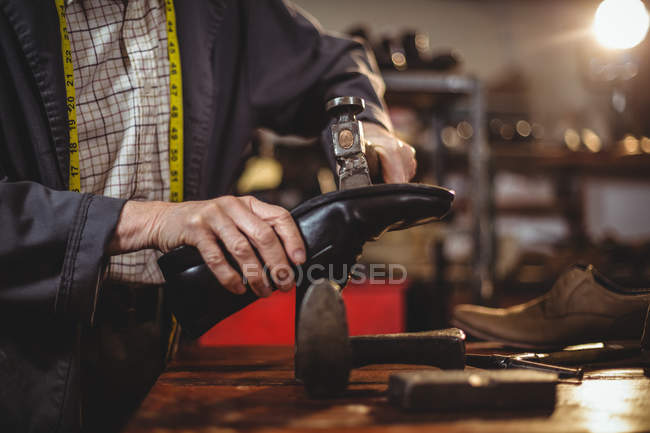 Mãos de sapateiro martelando em um sapato na oficina — Fotografia de Stock