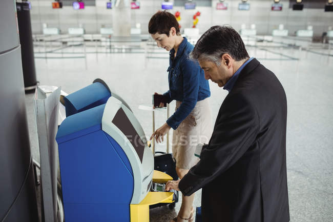 Uomini d'affari che utilizzano macchine self service per il check-in in aeroporto — Foto stock