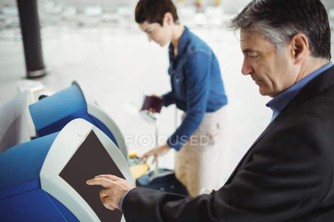 Empresario que utiliza la máquina de facturación de autoservicio en el aeropuerto - foto de stock