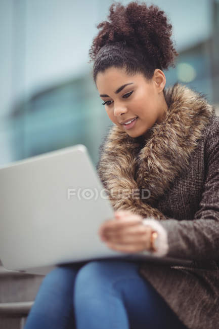 Low angle view of smart woman using laptop while sitting on steps — Stock Photo