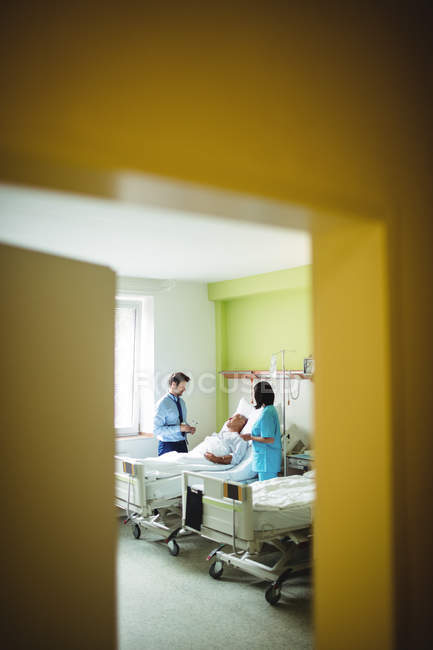 Médico y enfermera interactuando con el paciente en el hospital - foto de stock