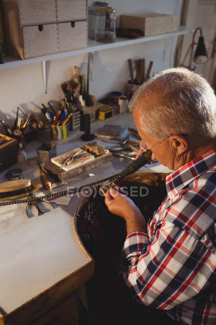 Goldsmith atencioso usando a máquina da peça da mão na oficina — Fotografia de Stock