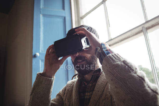 Joven usando gafas virtuales en casa cerca de la ventana - foto de stock