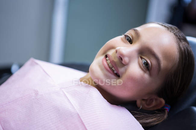 Sonriente paciente joven sentado en la silla del dentista en la clínica - foto de stock