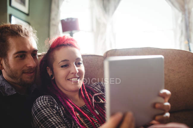 Романтическая молодая пара, сидящая дома за цифровым планшетом — стоковое фото