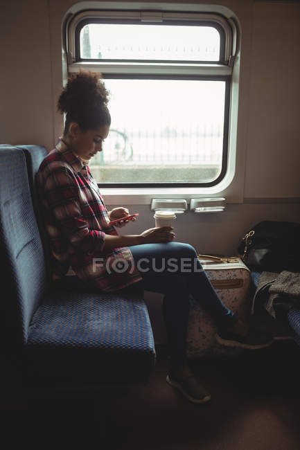 Toute la longueur de la jeune femme en utilisant le téléphone tout en étant assis dans le train — Photo de stock