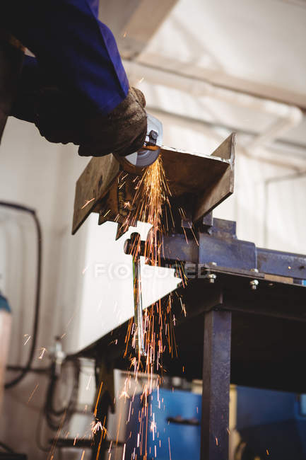 Geschnittenes Bild eines Schweißers, der in der Werkstatt Metall mit einem Elektrowerkzeug sägt — Stockfoto