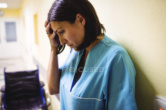 Депресивна медсестра стоїть в лікарняному коридорі — стокове фото