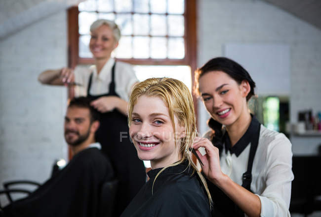 Портрет усміхненого перукаря розчісує клієнтське волосся в салоні — стокове фото