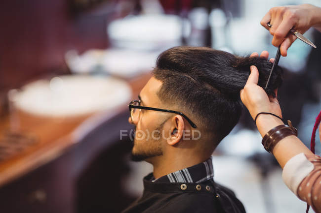 Homme se faire couper les cheveux avec des ciseaux dans le salon de coiffure — Photo de stock