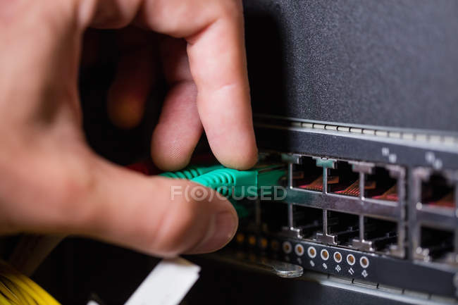 Primer plano del técnico femenino conectando Ethernet en sockets en la sala de servidores - foto de stock