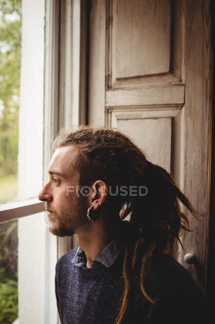 Close-up de hipster contemplado pela janela em casa — Fotografia de Stock