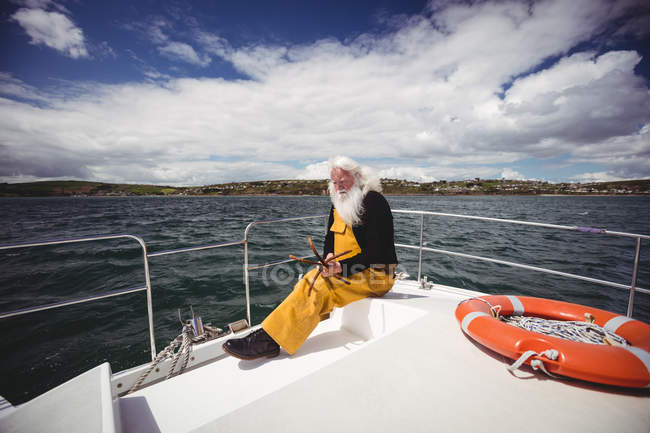 Nachdenklicher Fischer sitzt auf Fischerboot — Stockfoto
