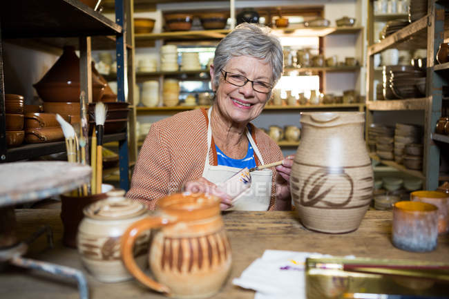Portrait of female potter painting on bowl in pottery workshop — Stock Photo