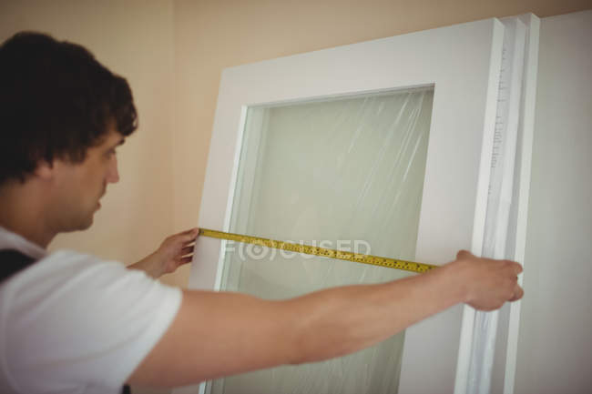 Carpenter measuring door at home — Stock Photo