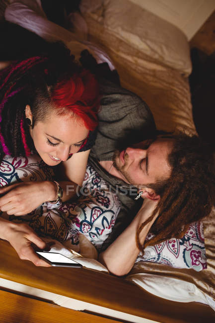 Високий кут зору молодої пари, використовуючи мобільний телефон на ліжку вдома — стокове фото