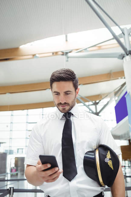 Pilote utilisant un téléphone portable dans le terminal de l'aéroport — Photo de stock