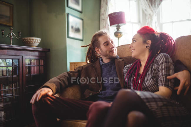 Счастливая пара разговаривает, сидя дома на диване — стоковое фото