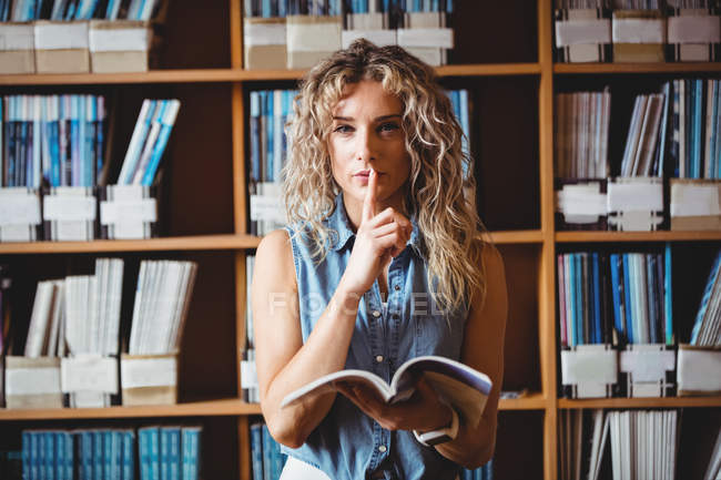 Beautiful woman showing silent gesture in library — Stock Photo