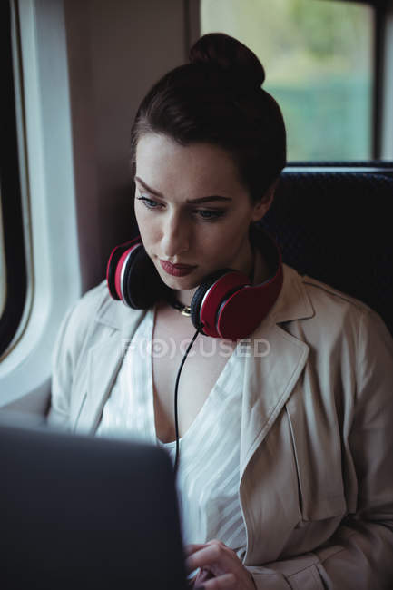 Mulher usando laptop enquanto sentado pela janela no trem — Fotografia de Stock