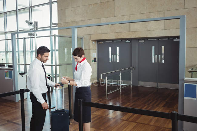 Empresário mostrando seu cartão de embarque no balcão de check-in no aeroporto — Fotografia de Stock