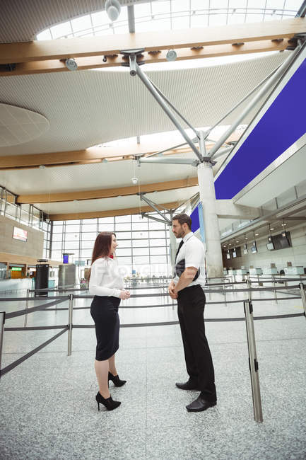 Pilot and flight attendant interacting with each other in airport terminal — Stock Photo