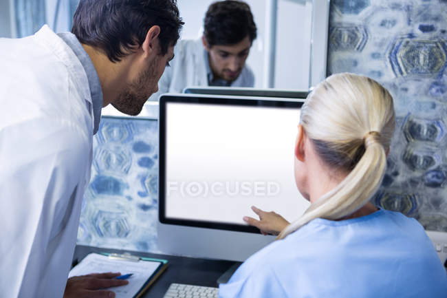 Dentist and dental assistant working at computer in dental clinic — Stock Photo