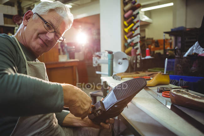 Uomo anziano calzolaio riparazione di una scarpa in officina — Foto stock