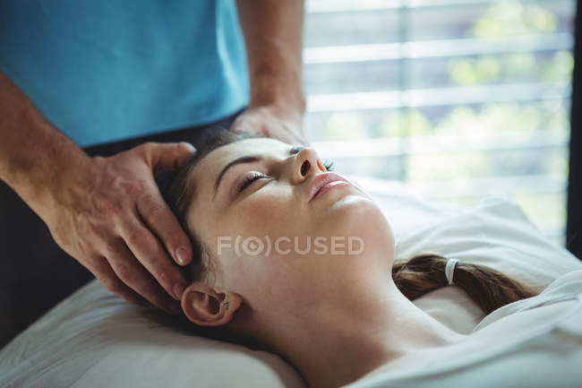Fisioterapeuta masculino dando massagem na cabeça para paciente do sexo feminino na clínica — Fotografia de Stock