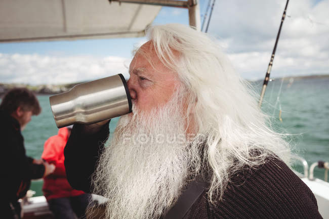 Fisherman drinking coffee from cup on boat — Stock Photo
