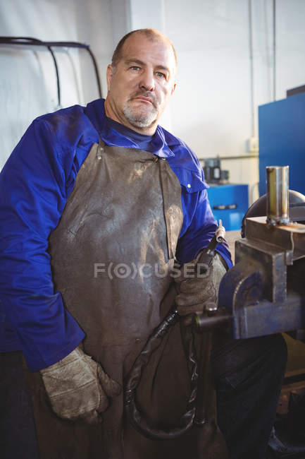 Retrato de soldador que sostiene la máquina de soldadura en el taller - foto de stock