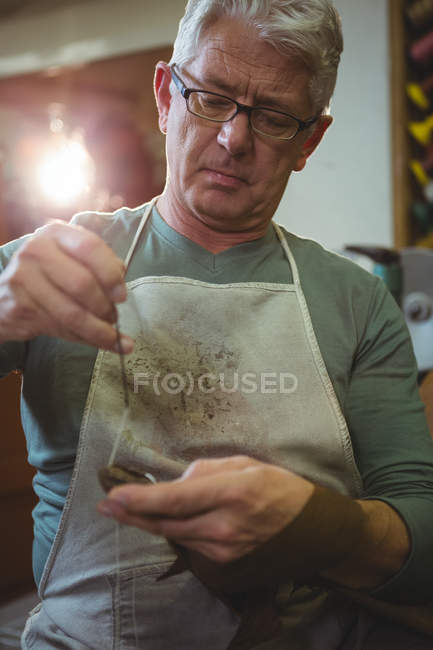 Zapatero costura suela del zapato con aguja en el taller - foto de stock