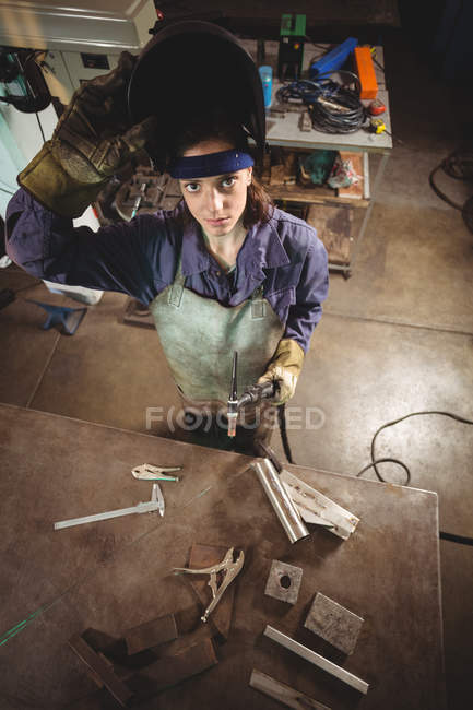 High angle view of Female welder holding welding torch in workshop — Stock Photo