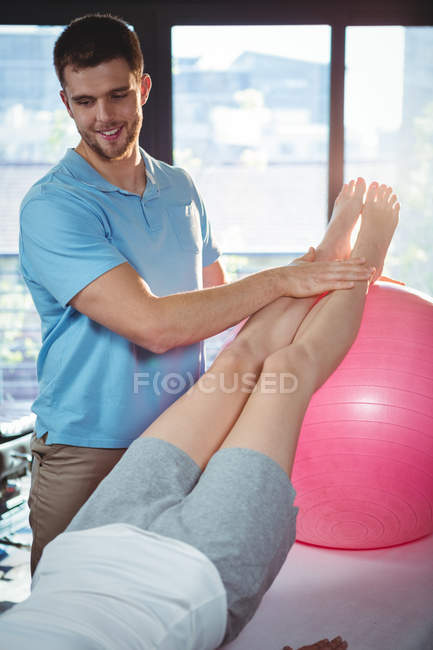 Male physiotherapist giving leg massage to female patient in clinic — Stock Photo